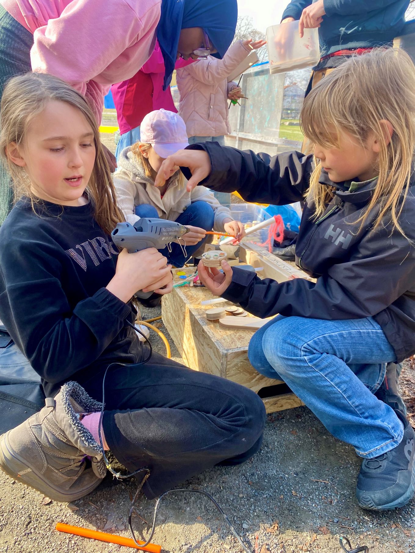 Foto: Charlotte Cappello Sylte Noen unge barn maler og limer små biler i tre.