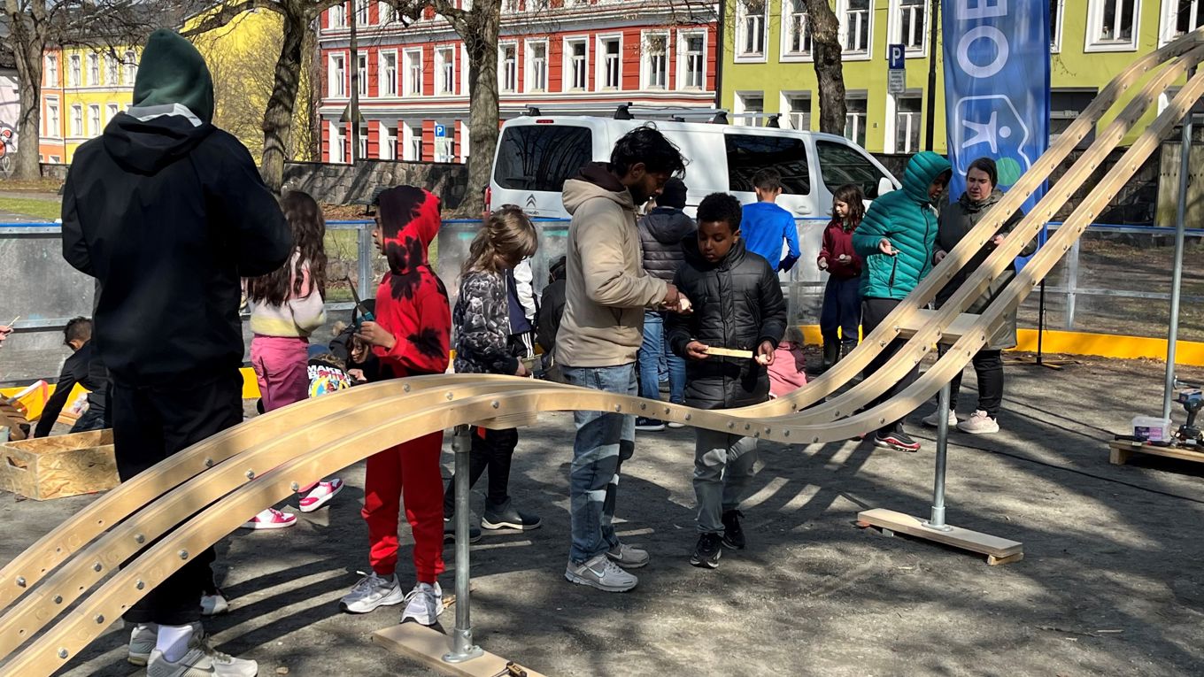Foto: Charlotte Cappello Sylte Elever står ved en bilbane som er lagd i treverk. Bilbanen står ute i parken ved skolen.