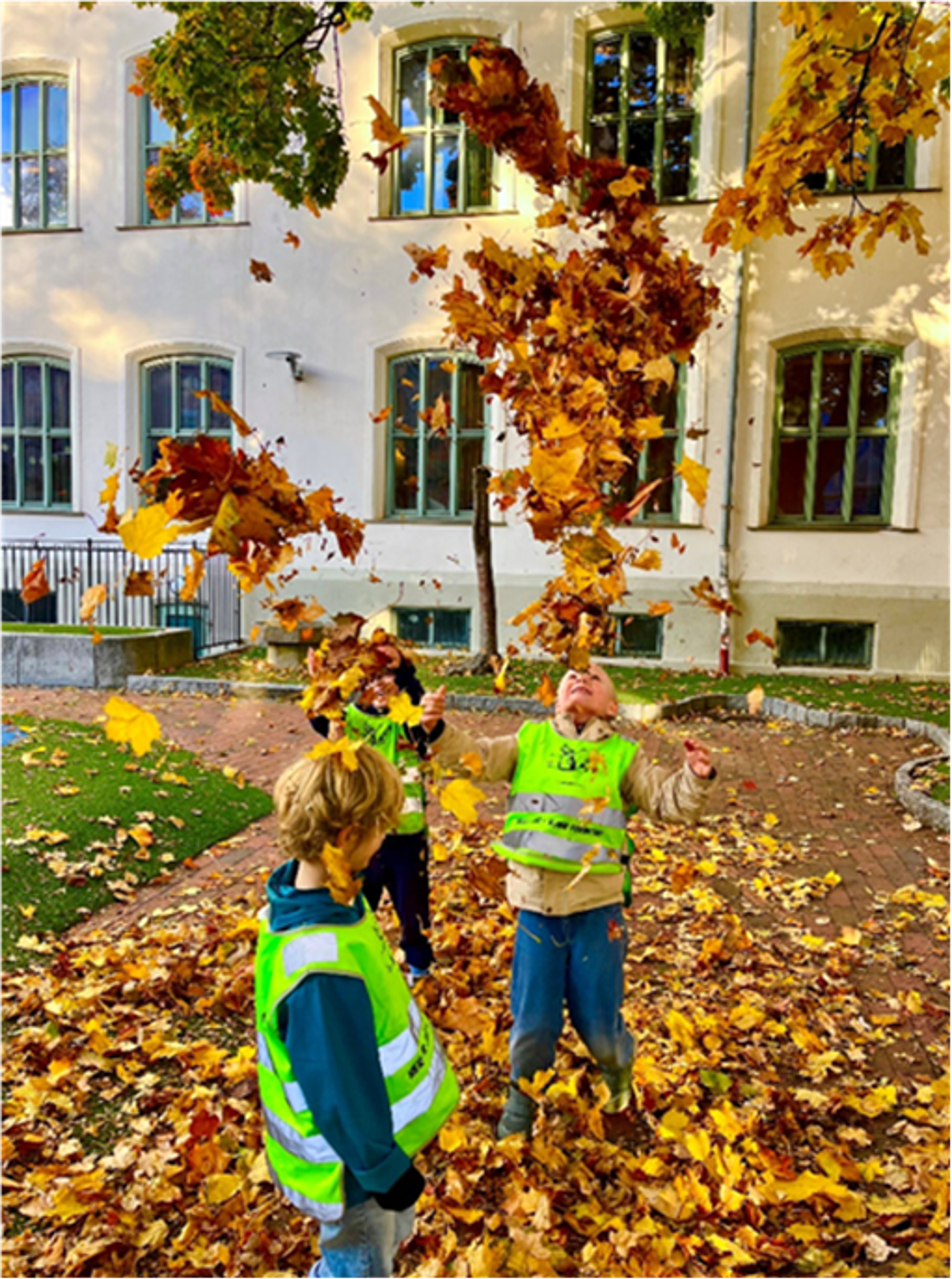 Foto: Elisabeth Wiik Et par barn som leker i en skolegård med løv på bakken.