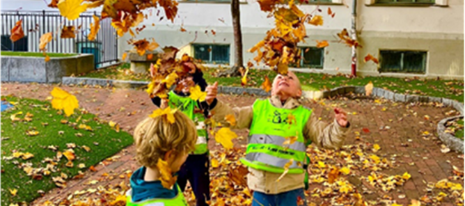 Foto: Elisabeth Wiik Et par barn som leker i en skolegård med løv på bakken.