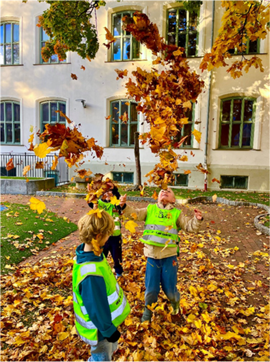 Foto: Elisabeth Wiik Et par barn som leker i en skolegård med løv på bakken.