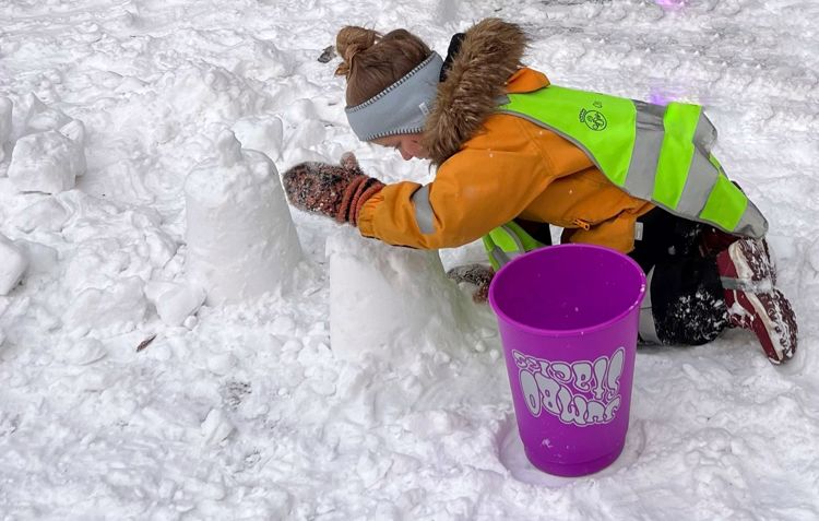 Et barn som bygger tårn i snøen