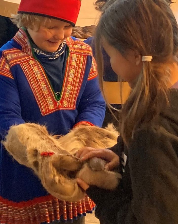 To elever på besøk ved Oslo samiske skole. En elev har på seg kofte fra Kautokeino. Sammen ser de på et par votter av reinsdyrskinn.