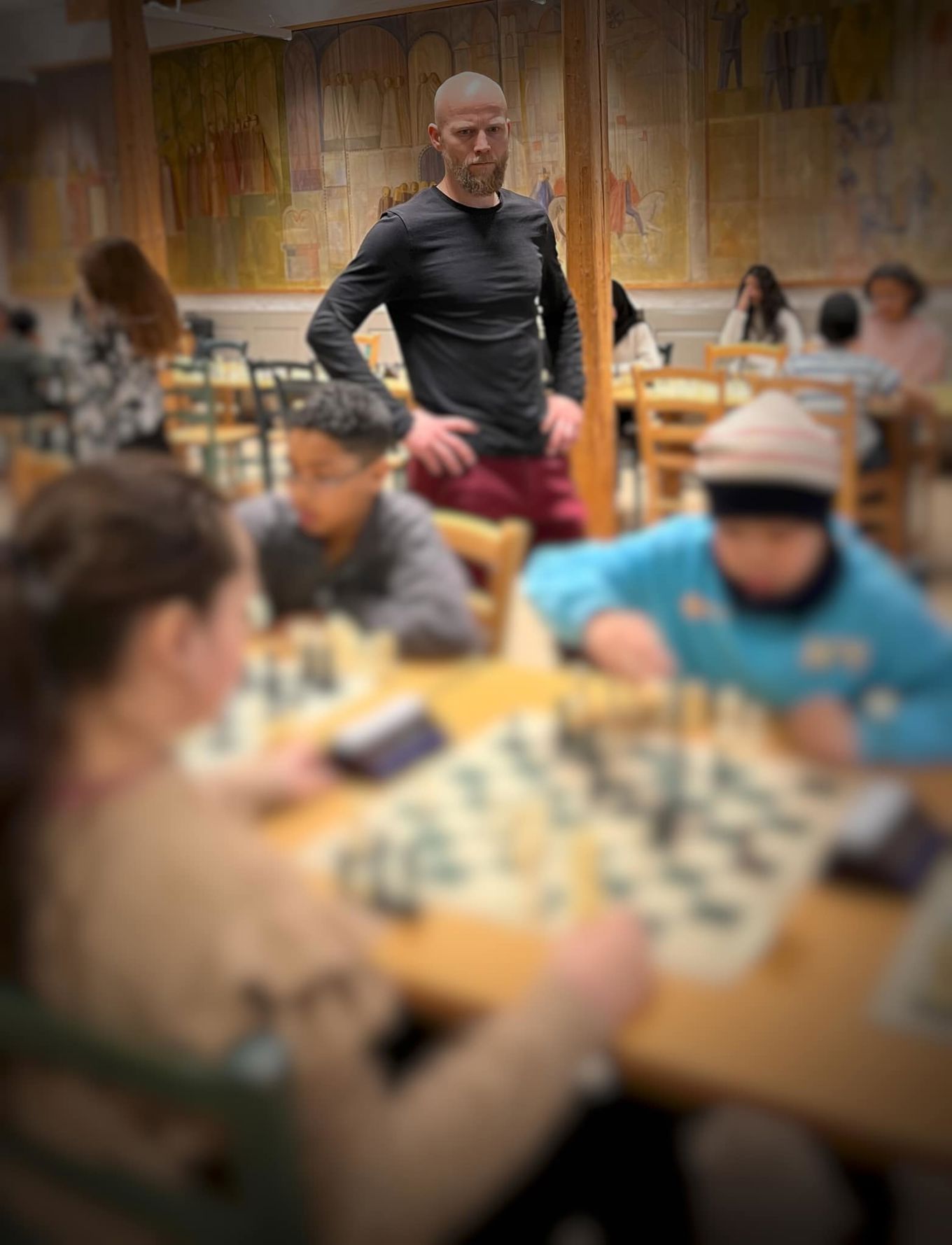 Sjakkturnering. Elever spiller sjakk mens en lærer står og følger med på spillet.