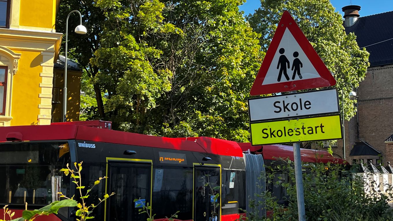 Foto: Geir Johansen En buss kjører forbi et fareskilt med tekst: Skole. Skolestart.