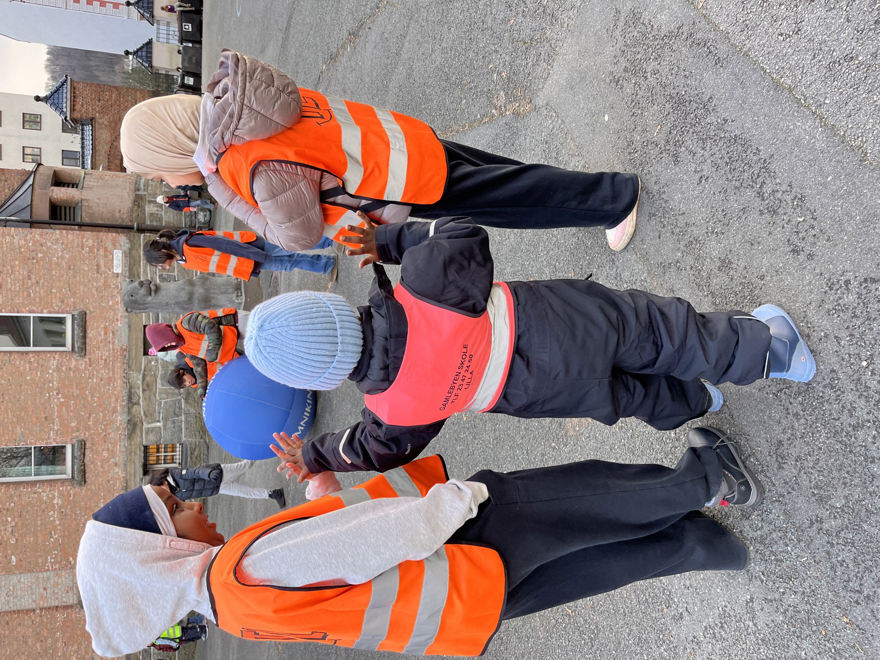 Foto: Elisabeth Wiik Barn står i ring i skolegården og leker med en stor ball.