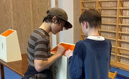 Foto: Terje Roll Elgsaas To elever ser ned i ei stemmeurne med riksvåpen på.