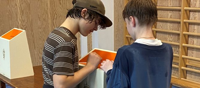Foto: Terje Roll Elgsaas To elever ser ned i ei stemmeurne med riksvåpen på.
